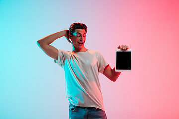 Image showing Young caucasian man\'s portrait on gradient blue-pink studio background in neon light