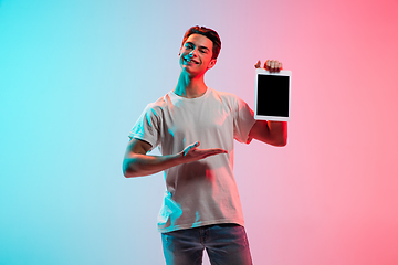 Image showing Young caucasian man\'s portrait on gradient blue-pink studio background in neon light