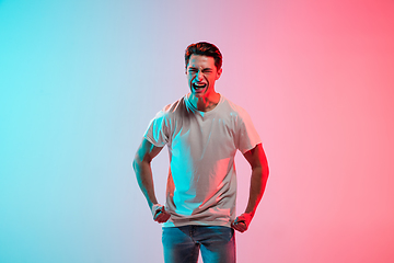 Image showing Young caucasian man\'s portrait on gradient blue-pink studio background in neon light