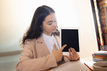 Image showing Young woman talking, working during videoconference with colleagues at home office