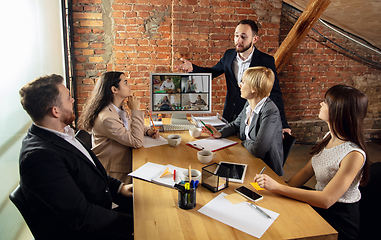 Image showing Young people talking, working during videoconference with colleagues at office or living room