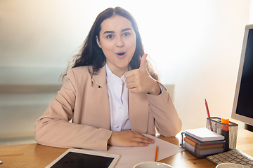 Image showing Young woman talking, working during videoconference with colleagues at home office