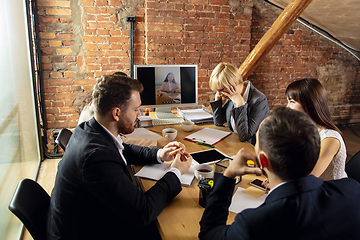 Image showing Young people talking, working during videoconference with colleagues at office or living room