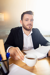 Image showing Young man talking, working during videoconference with colleagues at home office