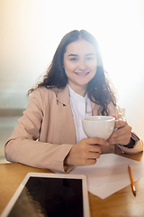 Image showing Young woman talking, working during videoconference with colleagues at home office