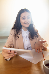 Image showing Young woman talking, working during videoconference with colleagues at home office