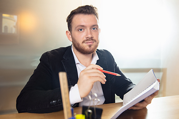 Image showing Young man talking, working during videoconference with colleagues at home office