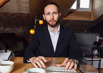 Image showing Young man talking, working during videoconference with colleagues at home office