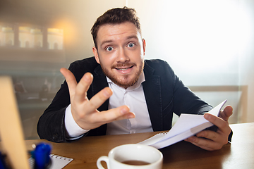 Image showing Young man talking, working during videoconference with colleagues at home office