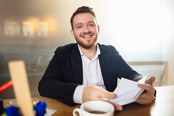 Image showing Young man talking, working during videoconference with colleagues at home office