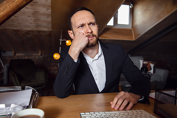 Image showing Young man talking, working during videoconference with colleagues at home office