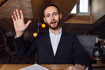 Image showing Young man talking, working during videoconference with colleagues at home office