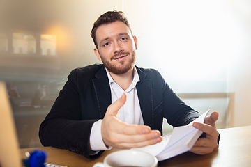 Image showing Young man talking, working during videoconference with colleagues at home office