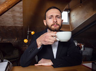 Image showing Young man talking, working during videoconference with colleagues at home office