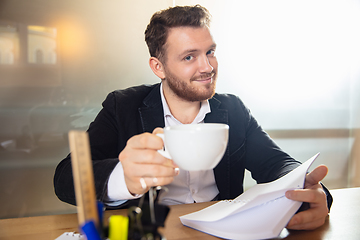 Image showing Young man talking, working during videoconference with colleagues at home office