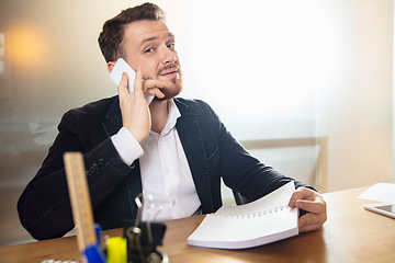 Image showing Young man talking, working during videoconference with colleagues at home office