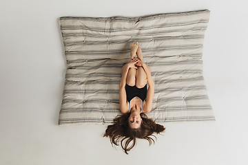 Image showing Beautiful young woman\'s portrait on grey mattress in studio. Having fun, happy, full length