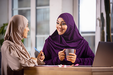 Image showing Happy two muslim women at home during lesson, studying near computer, online education