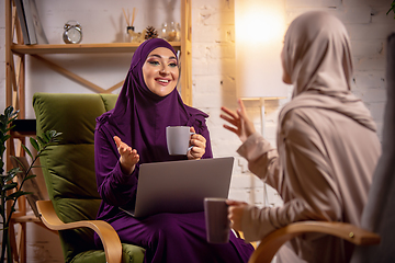 Image showing Happy two muslim women at home during lesson, studying with devices, online or home education