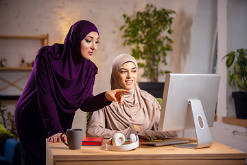 Image showing Happy two muslim women at home during lesson, studying near computer, online education