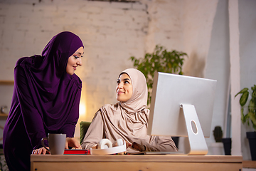 Image showing Happy two muslim women at home during lesson, studying near computer, online education