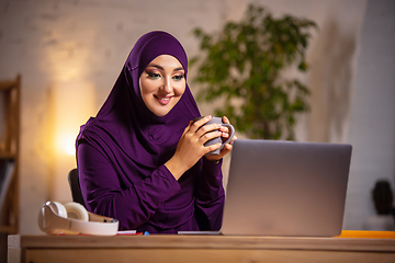 Image showing Happy muslim woman at home during online lesson. Modern technologies, remote education, ethnicity concept