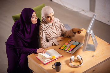 Image showing Happy two muslim women at home during lesson, studying near computer, online education