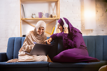 Image showing Happy two muslim women at home talking, smiling, having fun. Friendship, modern tech, emotions concept