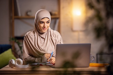 Image showing Happy muslim woman at home during online lesson. Modern technologies, remote education, ethnicity concept