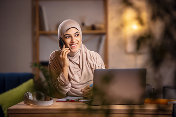 Image showing Happy muslim woman at home during online lesson. Modern technologies, remote education, ethnicity concept