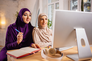 Image showing Happy two muslim women at home during lesson, studying near computer, online education