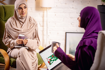 Image showing Happy two muslim women at home during lesson, studying with devices, online or home education