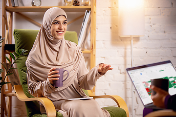 Image showing Happy muslim woman at home during online lesson. Modern technologies, remote education, ethnicity concept