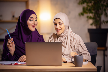 Image showing Happy two muslim women at home during lesson, studying near computer, online education