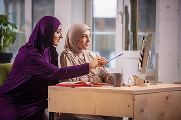 Image showing Happy two muslim women at home during lesson, studying near computer, online education