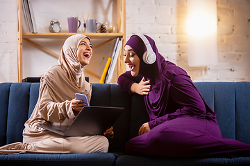 Image showing Happy two muslim women at home talking, smiling, having fun. Friendship, modern tech, emotions concept