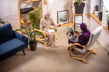 Image showing Happy two muslim women at home during lesson, studying with devices, online or home education