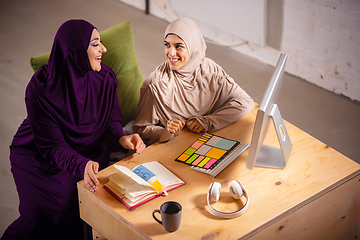 Image showing Happy two muslim women at home during lesson, studying near computer, online education