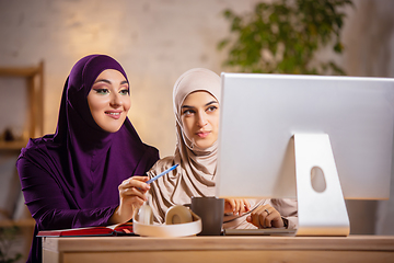 Image showing Happy two muslim women at home during lesson, studying near computer, online education