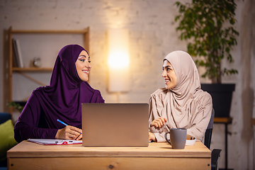 Image showing Happy two muslim women at home during lesson, studying near computer, online education