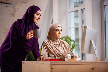 Image showing Happy two muslim women at home during lesson, studying near computer, online education