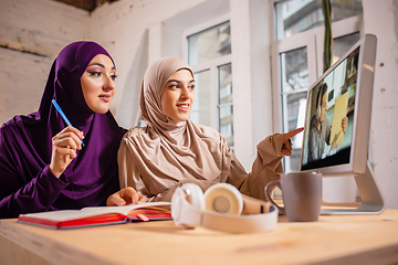 Image showing Happy two muslim women at home during lesson, studying near computer, online education