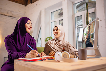 Image showing Happy two muslim women at home during lesson, studying near computer, online education