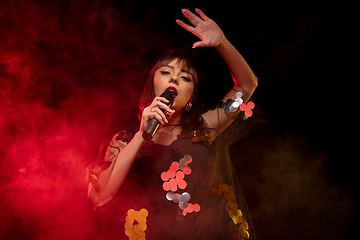 Image showing Caucasian female singer portrait isolated on dark studio background in neon light