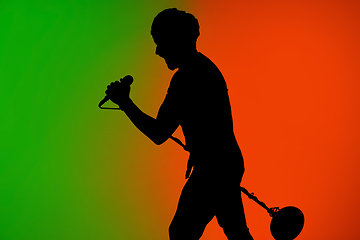 Image showing Silhouette of young caucasian male singer isolated on green-orange gradient studio background in neon light