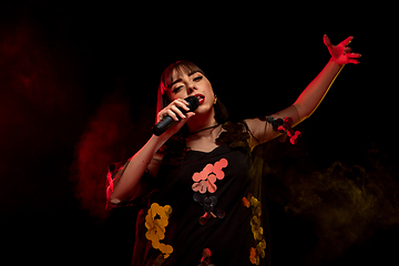 Image showing Caucasian female singer portrait isolated on dark studio background in neon light