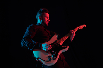 Image showing Silhouette of young caucasian male guitarist isolated on blue-pink gradient studio background in neon light