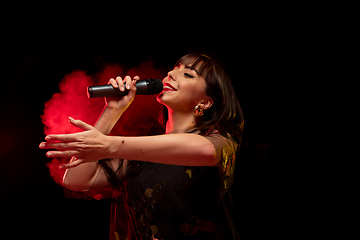 Image showing Caucasian female singer portrait isolated on dark studio background in neon light