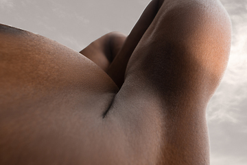 Image showing Detailed texture of human skin. Close up shot of young african-american male body like landscape with the sky background