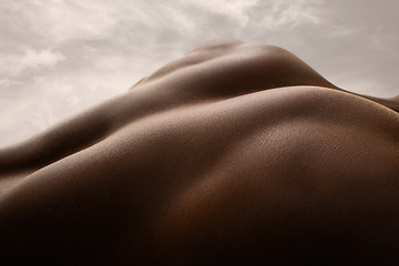 Image showing Detailed texture of human skin. Close up shot of young african-american male body like landscape with the sky background